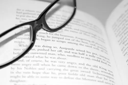 Reading glasses placed on an open book.