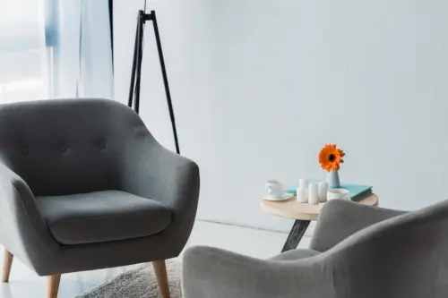 Cozy office decorated in light tones with gray chairs and a table.